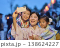 夏祭りでスマホで写真を撮る浴衣姿の母と姉妹 138624227