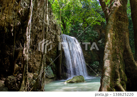 Pha Nam Tok, a scenic section of Erawan Waterfall in Kanchanaburi turquoise pool below surrounded by lush tropical forest towering trees. Pha Nam Tok, a scenic section of Erawan Waterfall in Kanchanaburi turquoise pool below surrounded by lush tropical forest towering trees. 138625220