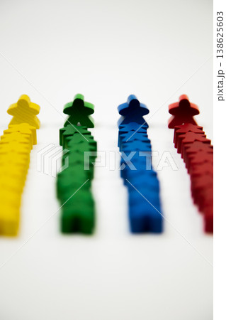 Side view of wooden multi-colored men in focus, who stand at the head of a column of smaller people on a white background. The concept of team competitions, social groups, managers, leaders. High 138625603