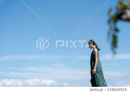 青空の下を歩くワンピースの女性 138626028
