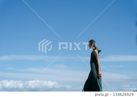 青空の下を歩くワンピースの女性 138626029