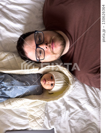 Father and newborn baby resting together on bed Father and newborn baby resting together on bed 138626364