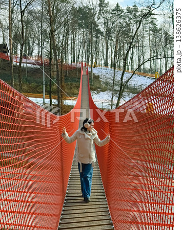 Person crossing orange suspension bridge 138626375