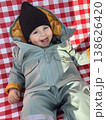 Smiling toddler in winter snowsuit on red checkered blanket 138626420