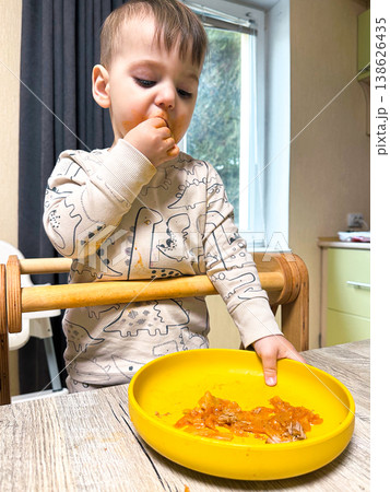 Toddler self-feeding messy meal in high chair 138626435