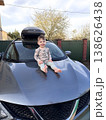 Toddler sitting on hood of gray suv in driveway 138626438