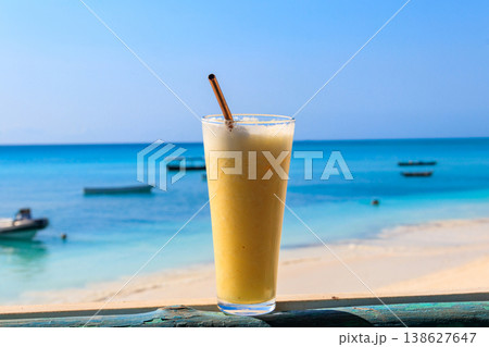 Glass of fresh juice by the ocean. Tropical vacations concept Glass of fresh juice by the ocean. Tropical vacations concept 138627647