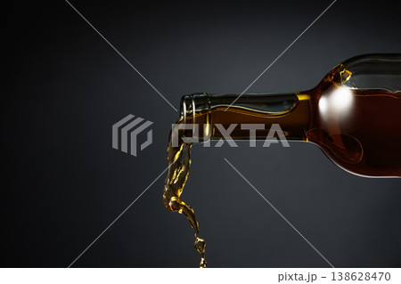 White wine of a rich amber color pours out of the bottle. 138628470