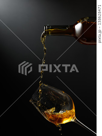White wine of rich amber color being poured into a glass. 138628471