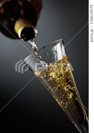 White sparkling wine is poured from a bottle into a glass. White sparkling wine is poured from a bottle into a glass. 138628474