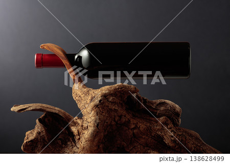 Unopened bottle of red wine and old weathered snag. Unopened bottle of red wine and old weathered snag. 138628499