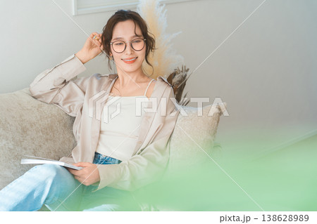 リビングのソファーに座り雑誌を読むオシャレなアジア人女性 138628989