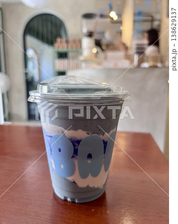 Healthy blue spirulina yoghurt smoothie shake in plastic takeaway cup on wooden table in cafe Healthy blue spirulina yoghurt smoothie shake in plastic takeaway cup on wooden table in cafe 138629137