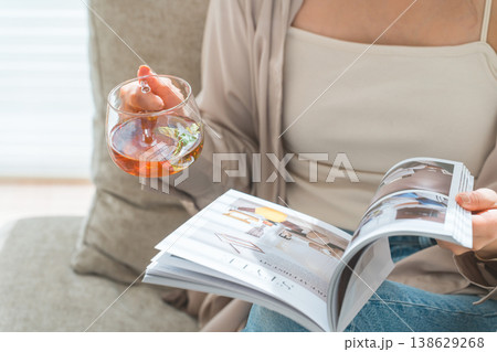 リビングのソファーに座りティータイムに雑誌を読むオシャレなアジア人女性 リビングのソファーに座りティータイムに雑誌を読むオシャレなアジア人女性 138629268