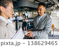 Professionals Clasp Hands Confidently. Office Colleagues Exchange Documents With Smiling Expressions 138629465