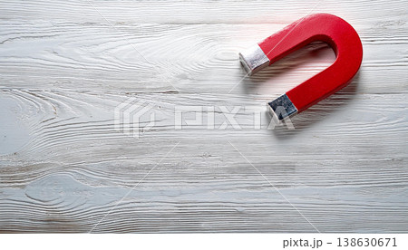 Attraction and Influence Concept , Red Magnet on White Wooden Surface Attraction and Influence Concept , Red Magnet on White Wooden Surface 138630671