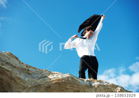 Cliff, business and man with celebration, excited and victory with holiday, smile and winning with promotion. Person, employee and consultant outdoor, nature and vacation with achievement or travel 138631029