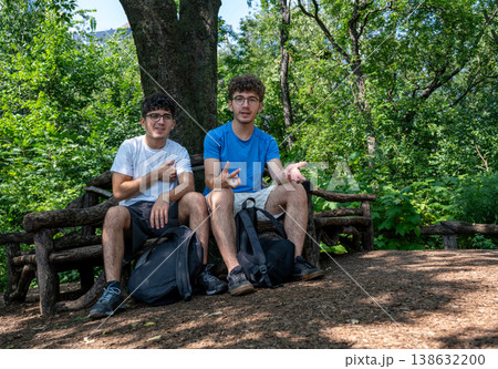 New york, usa august 14,2024. Two friends sitting on a rustic bench, enjoying their time together in the natural setting of central park, manhattan, new york 138632200