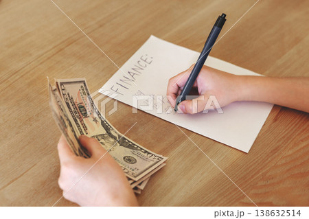 Kid hands holding dollar bills while writing finance calculations on paper, child learning budgeting and money skills, financial literacy education Kid hands holding dollar bills while writing finance calculations on paper, child learning budgeting and money skills, financial literacy education 138632514