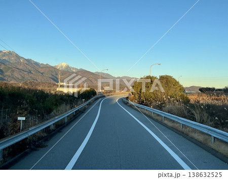 夕方の山並みへ続く高速道路カーブと地方風景（日本・無人） 138632525