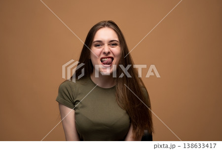 Young woman making a playful grimace while sticking out tongue, expressing a humorous and goofy mood Young woman making a playful grimace while sticking out tongue, expressing a humorous and goofy mood 138633417