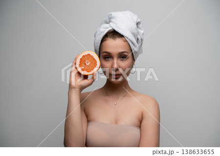 Young woman with a towel on her head holding a fresh grapefruit expressing a concept of natural beauty, wellness, organic skincare, and a healthy morning routine 138633655