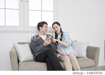 リビングでスマホを見て会話するカップル 138633758