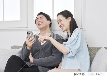 リビングでスマホを見て会話するカップル 138633759