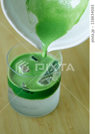 fresh matcha tea, green tea pouring on a glass of coconut water on white wooden table. fresh matcha tea, green tea pouring on a glass of coconut water on white wooden table. 138634083