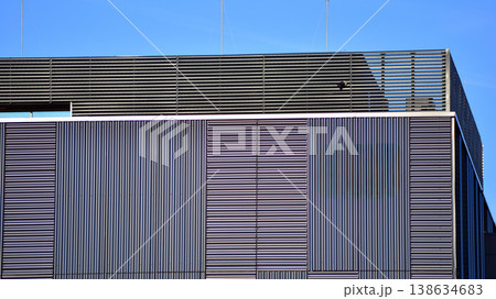The futuristic building has engineered vertical cladding steel frame panels. The exterior wall of a contemporary commercial style building with aluminum metal composite panels. The futuristic building has engineered vertical cladding steel frame panels. The exterior wall of a contemporary commercial style building with aluminum metal composite panels. 138634683