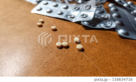 Loose Yellow Tablets with Used Blister Packs in Background 138634716