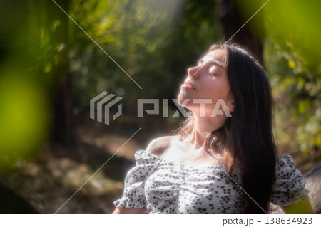 Relaxed young woman with closed eyes in forest light 138634923