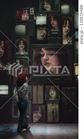 Woman observing multiple emotional faces on retro television screens in dark room Woman observing multiple emotional faces on retro television screens in dark room 138635486