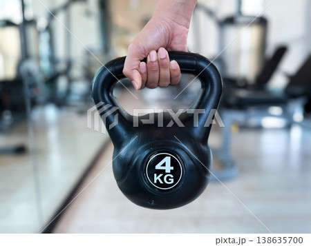 a person holding a 4 kg black kettlebell in a gym. High quality photography showing strength training, fitness workout, bodybuilding, weightlifting, and healthy lifestyle concept 138635700