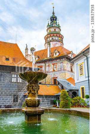 Castle tower stands tall in Cesky Krumlov. Water flows from a fountain in the foreground. The buildings around show the town's rich history and architecture. Visitors enjoy summer in this UNESCO site. Castle tower stands tall in Cesky Krumlov. Water flows from a fountain in the foreground. The buildings around show the town's rich history and architecture. Visitors enjoy summer in this UNESCO site. 138637938