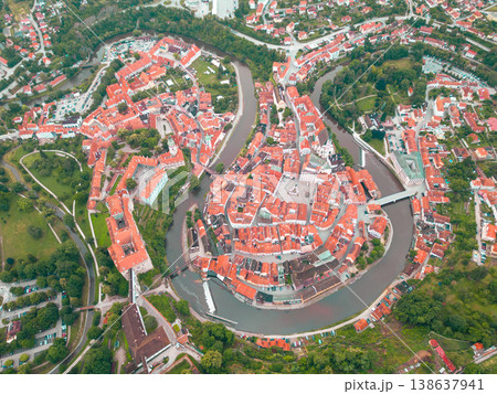 This aerial view showcases Cesky Krumlov, a UNESCO heritage site, with its picturesque medieval architecture and winding Vltava River surrounded by lush greenery during a bright morning. 138637941