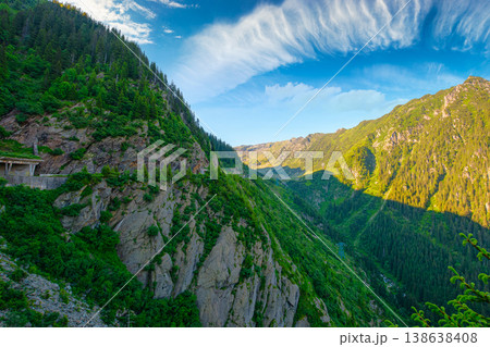 Valley in summer mountains. Gorgeous mountainous landscape of Carpathians. Rocky cliffs and forested slopes under blue sky. Scenery of Fagaras ridge of Southern Carpathian mountains of Romania, Sibiu Valley in summer mountains. Gorgeous mountainous landscape of Carpathians. Rocky cliffs and forested slopes under blue sky. Scenery of Fagaras ridge of Southern Carpathian mountains of Romania, Sibiu 138638408