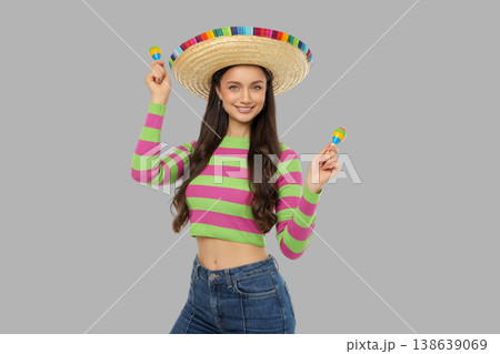 Cinco de Mayo, Woman in sombrero holds maracas, colorful shirt Cinco de Mayo, Woman in sombrero holds maracas, colorful shirt 138639069