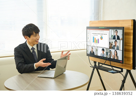 オフィスで大型モニターを使ってオンラインミーティングでプレゼンをする若いビジネスマン オフィスで大型モニターを使ってオンラインミーティングでプレゼンをする若いビジネスマン 138639352
