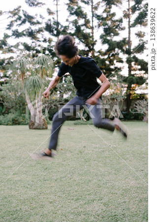 Energetic Young Person Leaping with Joy on Green Grass 138639622