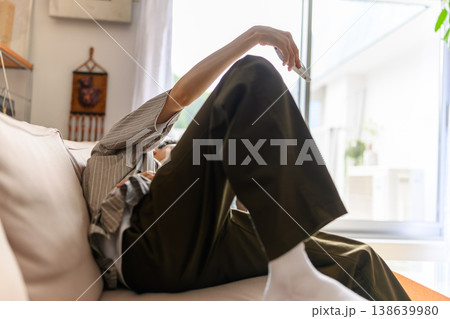 ソファでくつろぎながら手を伸ばす男性 138639980