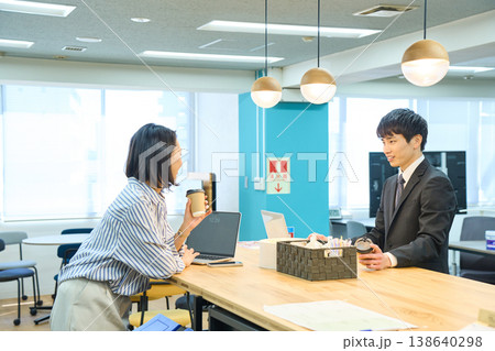 オフィスの休憩室でコーヒーを片手に笑顔でコミュニケーションをとる男女 オフィスの休憩室でコーヒーを片手に笑顔でコミュニケーションをとる男女 138640298