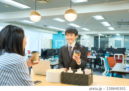 オフィスのカフェスペースでコーヒーを飲みながら同僚と談笑する男性社員 オフィスのカフェスペースでコーヒーを飲みながら同僚と談笑する男性社員 138640301