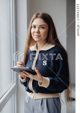 Young female interior designer working on digital tablet with stylus, planning home renovation project by the window. 138641353