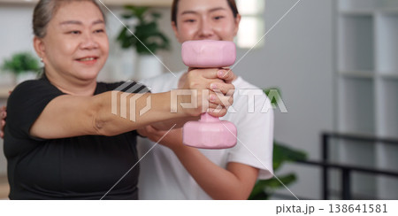 Senior woman lifting weights with trainer's support Senior woman lifting weights with trainer's support 138641581