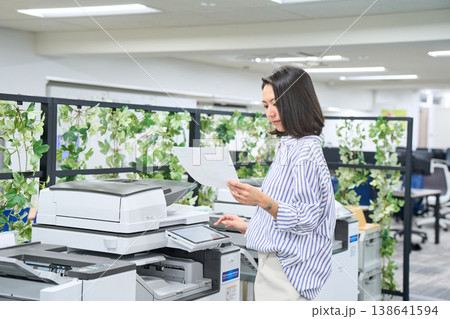 オフィスの複合機でプリントした資料を確認するビジネスウーマン 138641594