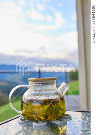 Tea being served in a glass teapot with a mountain view in the background on a cloudy day Tea being served in a glass teapot with a mountain view in the background on a cloudy day 138641686
