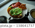 Enjoying avocado toast with coffee and sides at a cozy cafe in the morning light 138641737