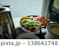 Enjoying avocado toast with coffee and sides at a cozy cafe in the morning light 138641748
