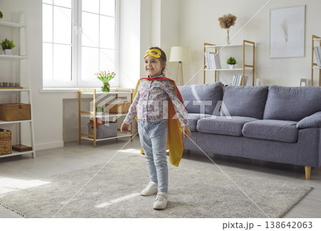 Little girl in yellow mask and cape playing superhero in living room at home Little girl in yellow mask and cape playing superhero in living room at home 138642063